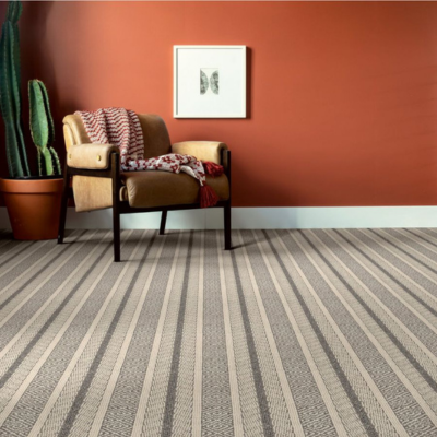 Stylish interior with striped cream and charcoal carpet, terracotta wall, and mid-century modern leather armchair, emphasizing the bold flooring pattern.